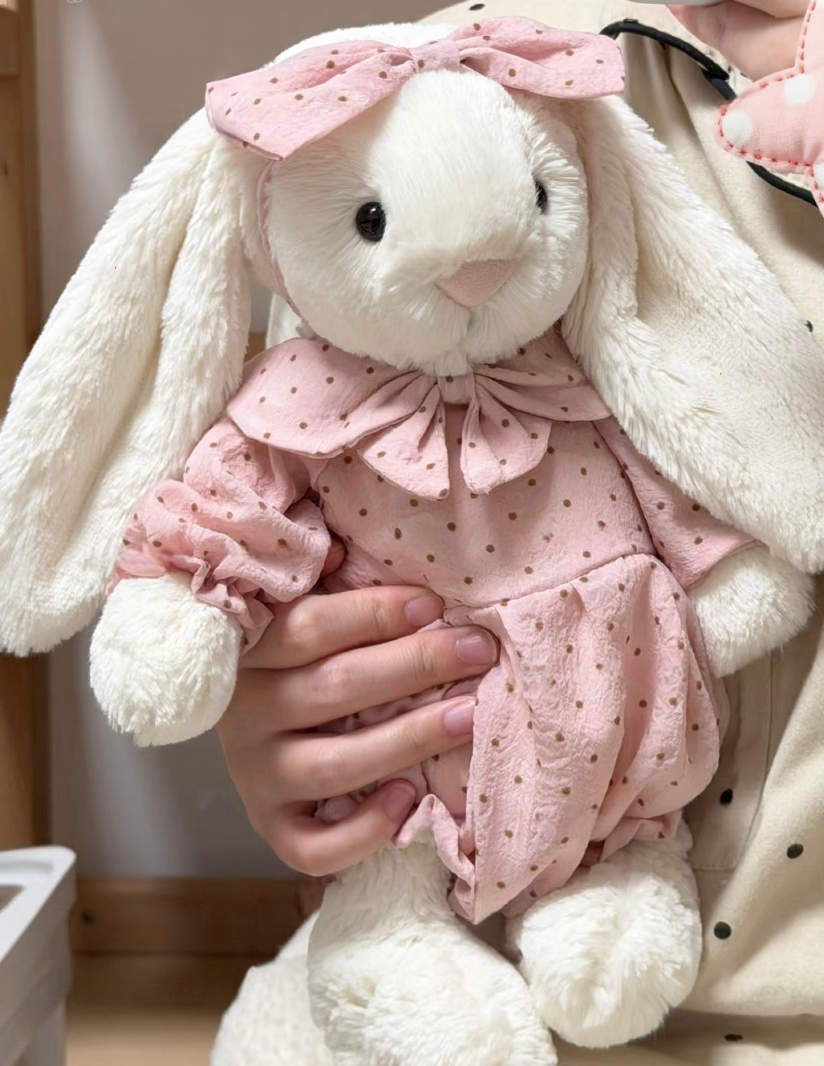 Blue polka dot romper set on white bunny plush - held close view