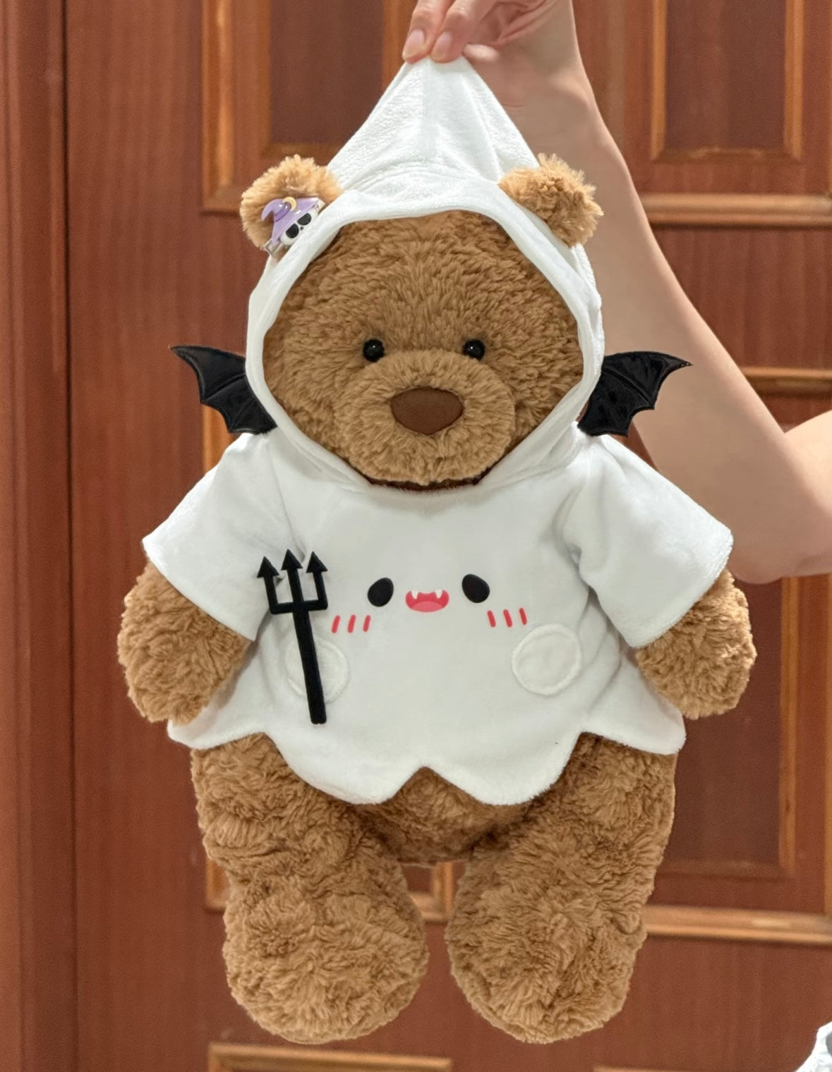 Front view of plush bear in white ghost hoodie with vampire face embroidery and black bat wings