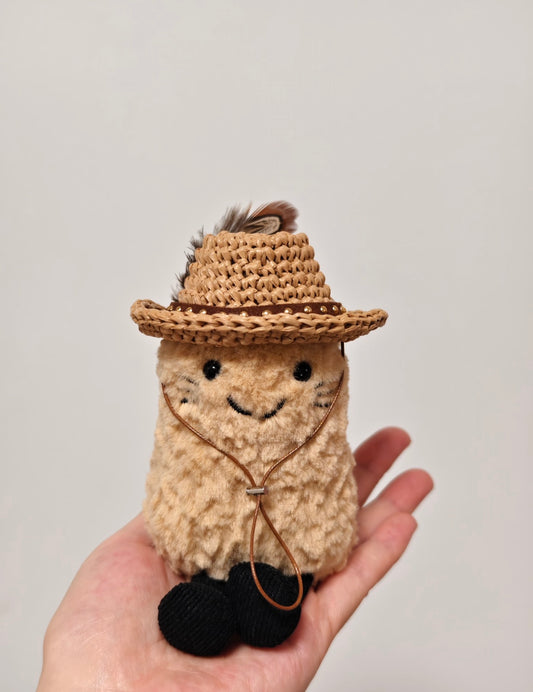 Small plush toy wearing mini woven straw cowboy hat with feather accent and brown band