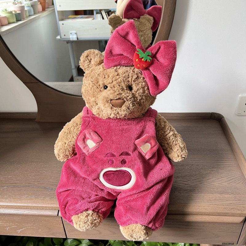 Brown plush bear wearing hot pink strawberry dungaree set with matching bow headband
