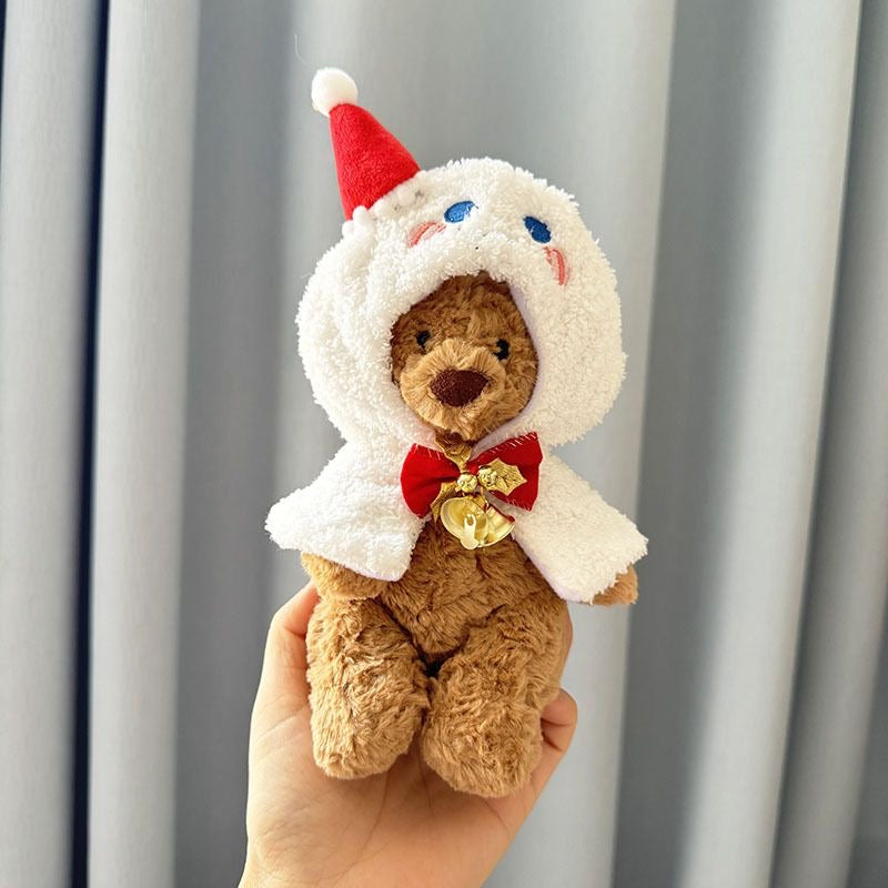 Brown plush bear wearing white fluffy ghost hooded cape with embroidered face, red Santa hat and golden jingle bell bow