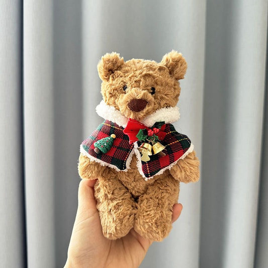 Brown plush bear wearing red and green tartan Christmas cape with white faux-fur trim, red bow, Christmas tree charm and golden jingle bells