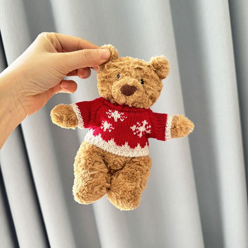 Brown plush bear wearing red knitted Christmas jumper with white snowflake motifs and cream ribbed trim
