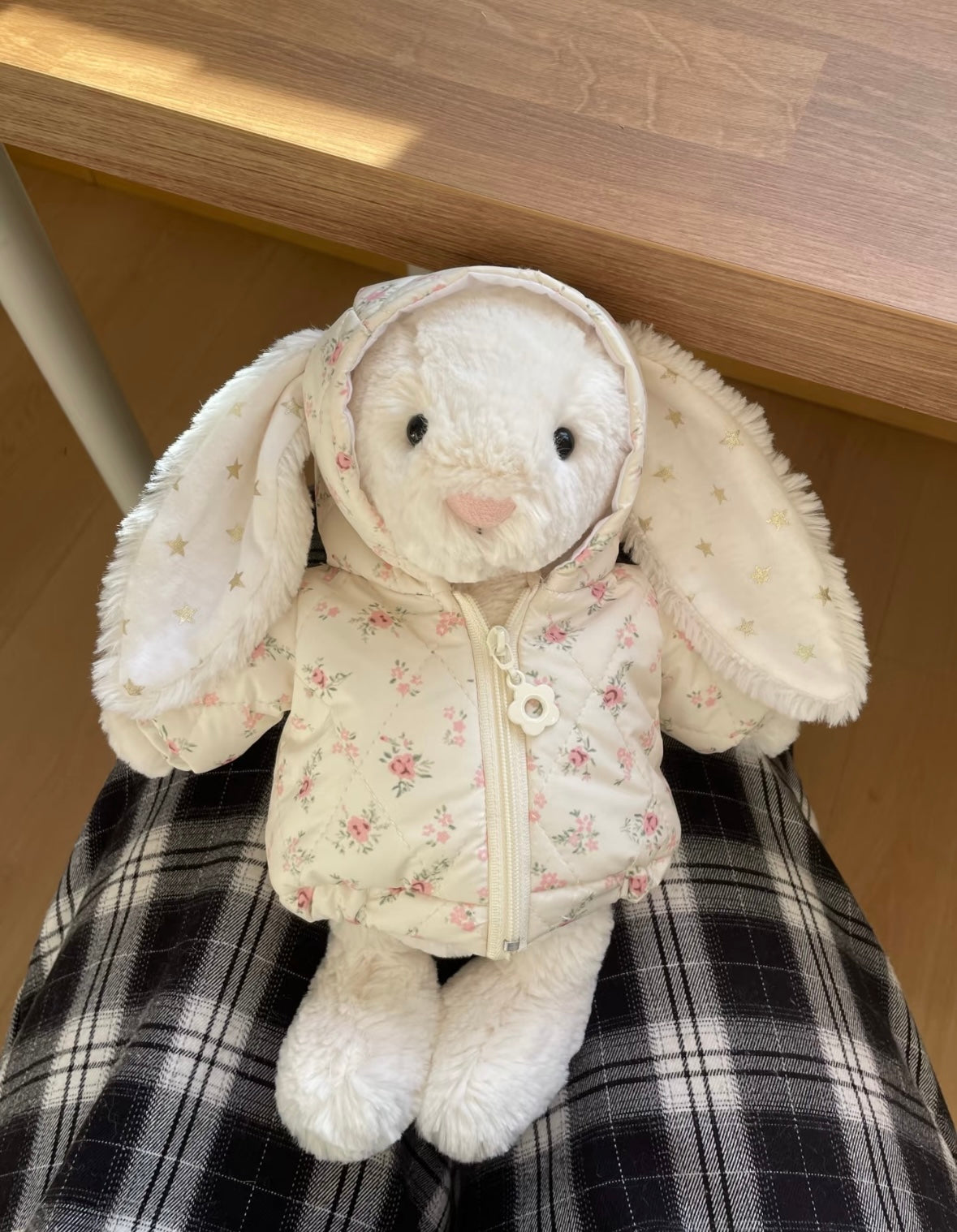 White Bashful Bunny wearing cream floral puffer jacket with hood, front view