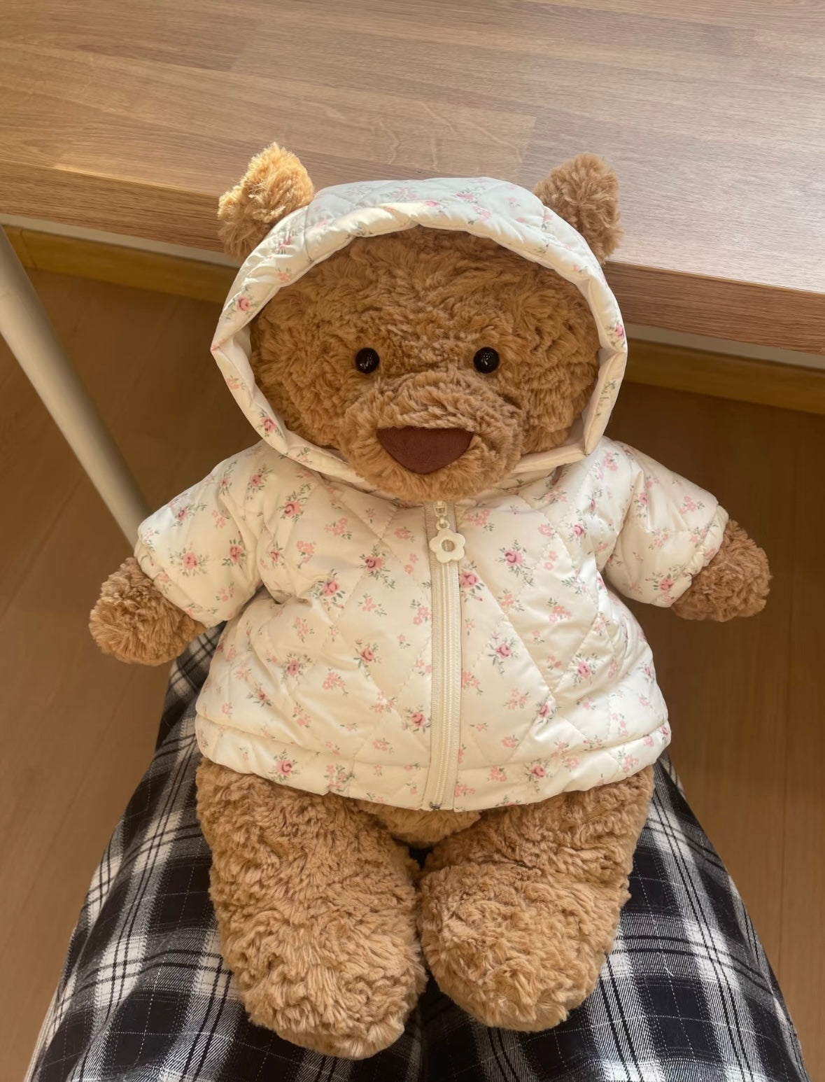 Brown teddy bear wearing cream floral puffer jacket with hood, front view