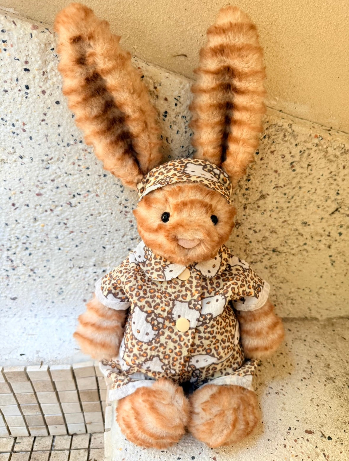 Jellycat bunny in Hello Kitty leopard print outfit, close-up front view outdoors