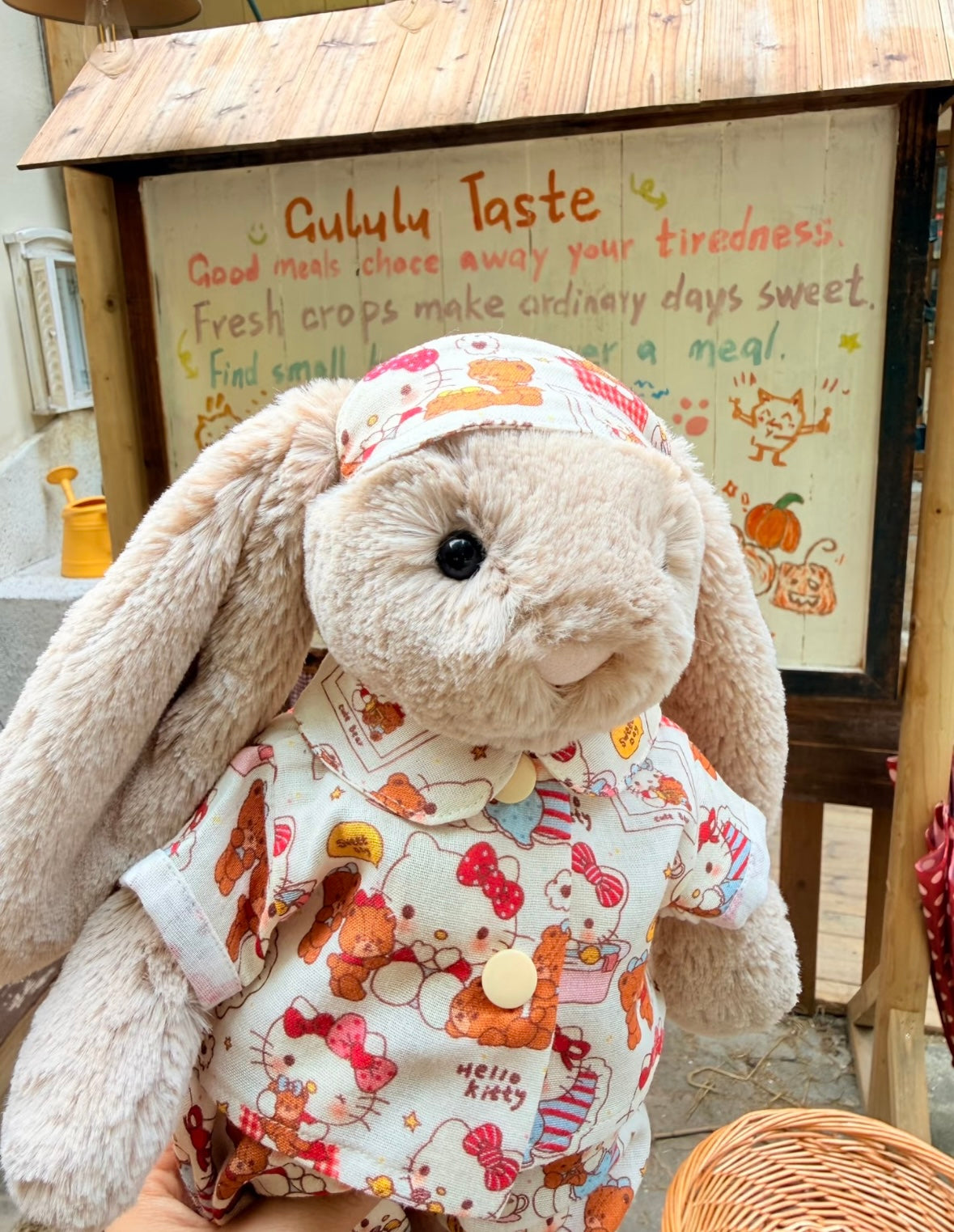 Bashful Bunny wearing Hello Kitty pyjama set in a wicker basket with autumn vegetables