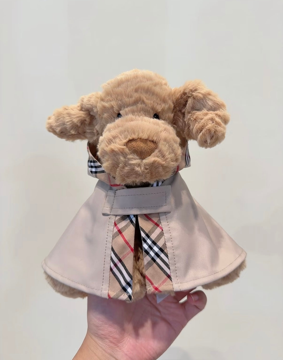 Blue grey plush bunny in a stone trench cape with popped check-lined collar