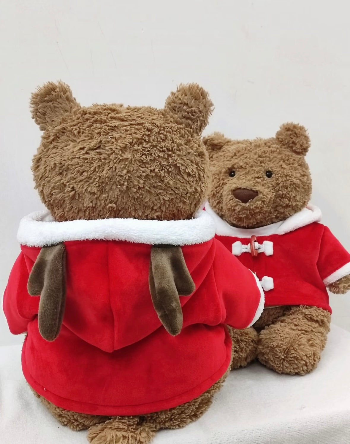 Large Bartholomew Bear wearing red Santa hooded duffle coat, close-up front view