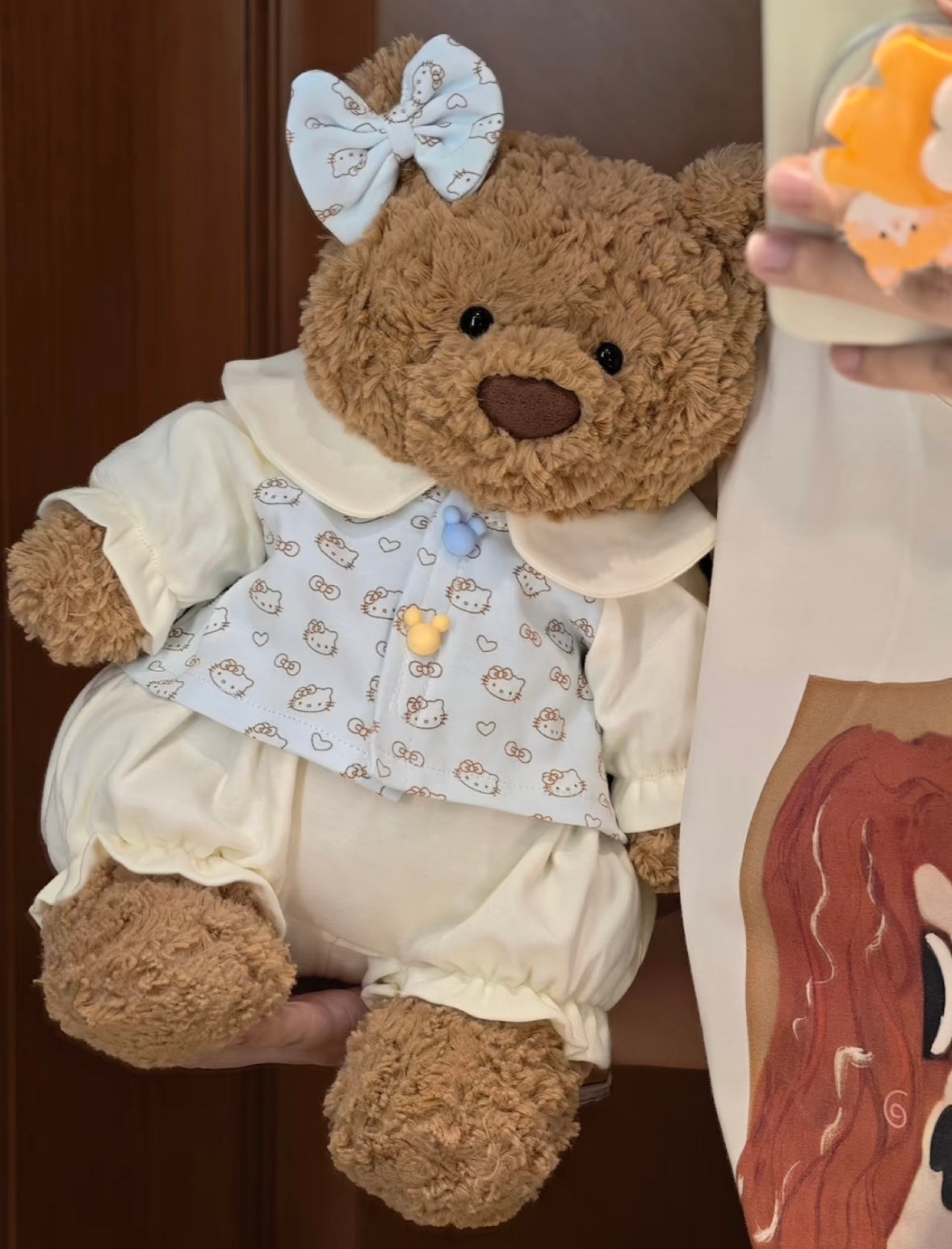 Bartholomew Bear wearing blue Hello Kitty romper set with blue bow hair clip, front view